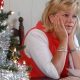 Woman looking fed up, with head in hands beside Christmas tree