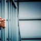 Man holding onto prison cell bars