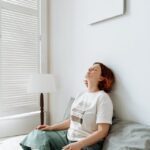 Yound woman sitting cross-legged on her bed with eyes closed