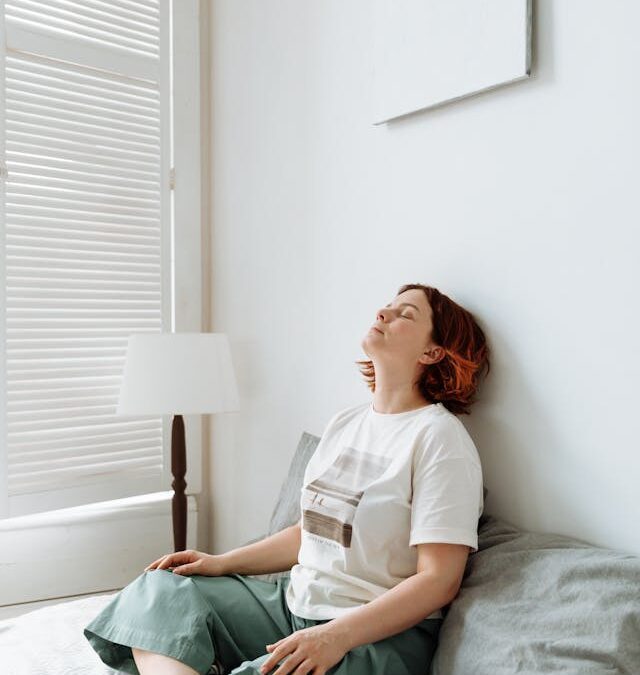 Yound woman sitting cross-legged on her bed with eyes closed